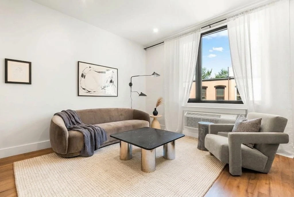 Small apartment living room with a compact sofa, accent chair, wooden coffee table, and clear walkway.