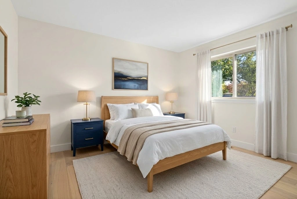 Navy blue bedroom nightstands with brass lamps, a natural oak bed, and white bedding